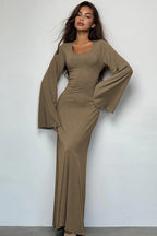 Woman wearing a long-sleeved, ribbed maxi dress with bell sleeves in a taupe color.