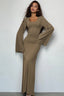 Woman wearing a long-sleeved, ribbed maxi dress with bell sleeves in a taupe color.
