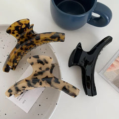 three hair claw clips in tortoiseshell, tan, and black on a white surface