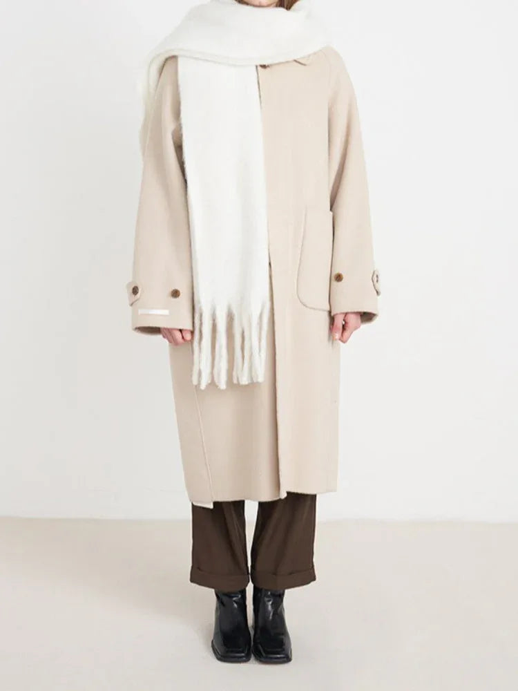 Full body shot of a woman wearing a beige coat and a white fluffy scarf