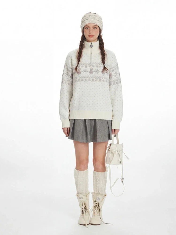 Model wearing a white knit sweater with a Fair Isle pattern and snowman graphic, paired with a grey pleated skirt, white knee-high socks, and cream ankle boots.