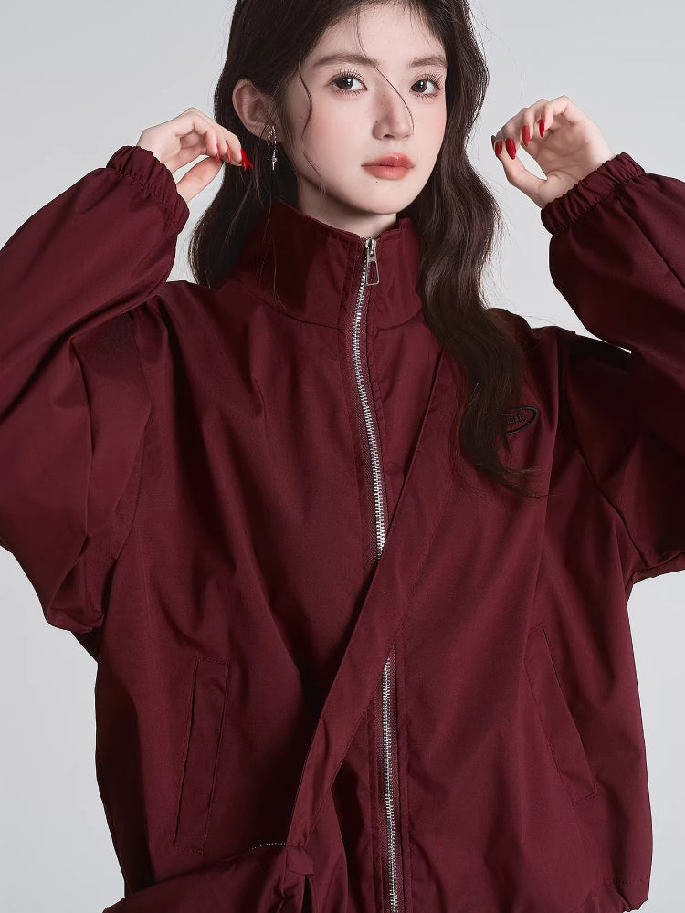 Front view of a woman adjusting the collar of her maroon bomber jacket
