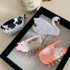 Decorative hair clips featuring a pig, cow, chicken, and swan arranged on a framed canvas