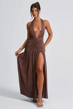 woman wearing a brown halter maxi dress with a deep v-neckline and high slit, showing the side profile