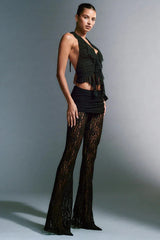 Model wearing a black lace skirt and flared pants with a ruffled halter top.