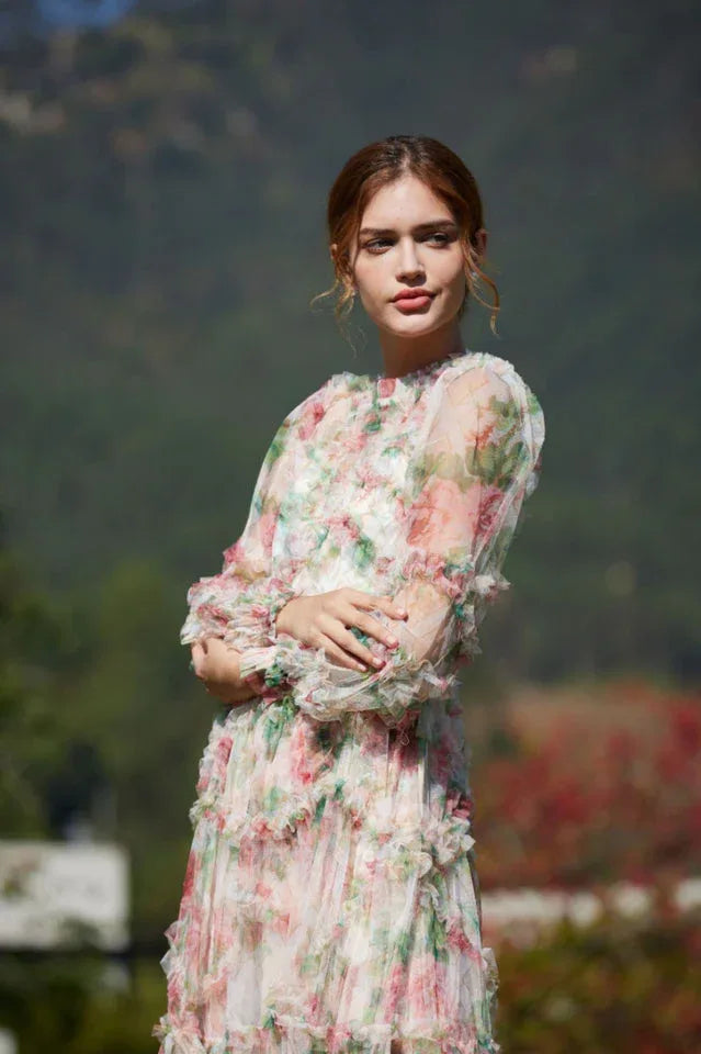 Close-up of a woman wearing a floral print chiffon gown with tiered ruffles and bishop sleeves.