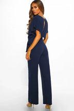 Back view of a woman in a navy blue wide leg jumpsuit with a keyhole detail