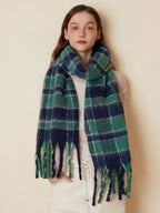 Woman wearing a green and navy plaid scarf draped around her neck, styled with a white top.