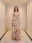 Woman wearing a cream-colored floral print maxi dress with spaghetti straps and a thigh-high slit, standing in a hallway.