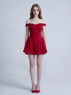 Woman in a red off-the-shoulder mini dress standing against a white background