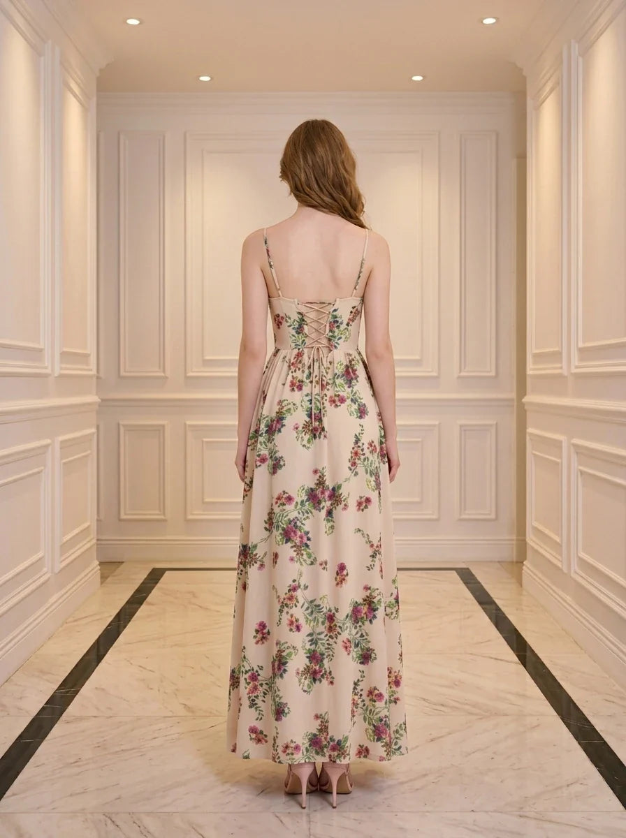 Back view of a woman in a cream-colored floral print maxi dress with spaghetti straps and a lace-up back detail, standing in a hallway.