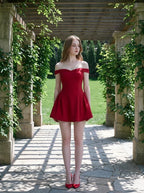 Woman in a red off-the-shoulder mini dress standing under a pergola