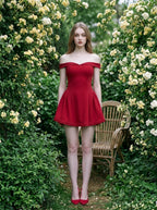 Woman in a red off-the-shoulder mini dress standing in a garden with yellow flowers