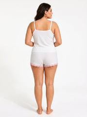 Back view of a woman in a white ribbed camisole and shorts pajama set with pink lace trim.