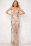 Woman in a long nude sequined and appliqued sheer dress with a high slit and deep V-neck, hands on hips