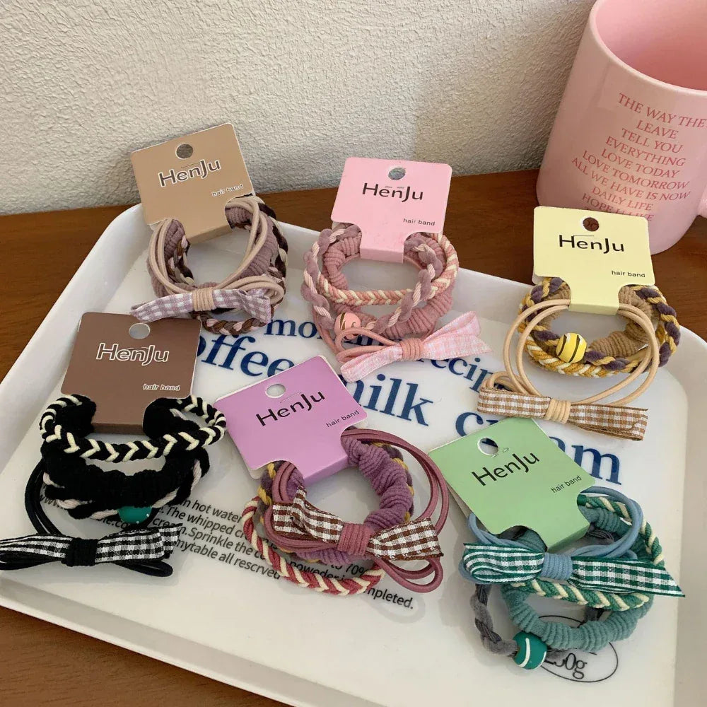 Various hair ties with decorative bows and braided elements shown on a tray.