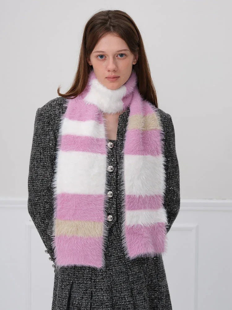 Woman wearing a pink, white, and beige striped fuzzy scarf over a dark textured jacket.