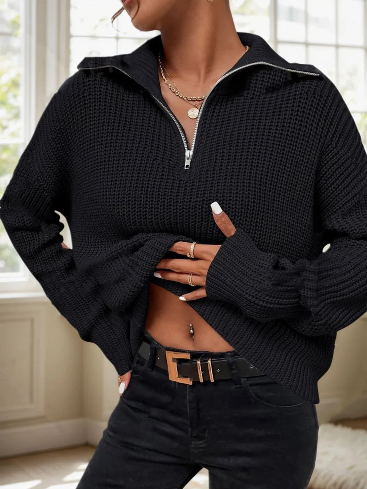 Woman wearing a black ribbed knit sweater with a half-zip closure and collar.