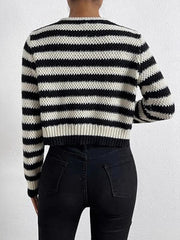 Back view of a woman wearing a black and white striped cropped knit cardigan and black jeans.
