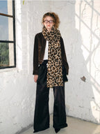 Full body shot of a model in a brown jacket, leopard print scarf, and black wide-leg pants.