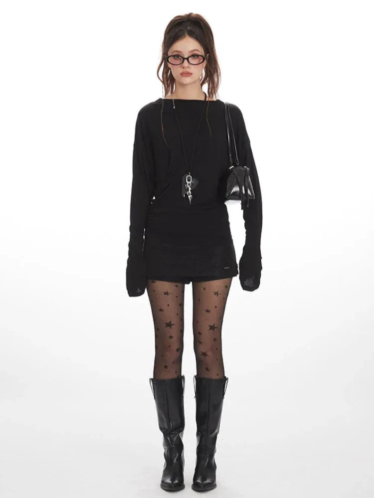 Woman wearing a black long-sleeve mini dress, star-patterned tights, and black boots, posing against a white background.