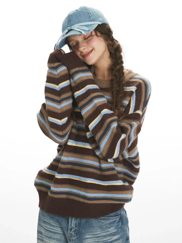 Model posing with eyes closed and head resting on hands, wearing a striped sweater.