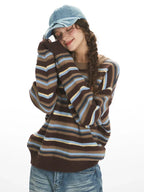 Model posing with eyes closed and head resting on hands, wearing a striped sweater.
