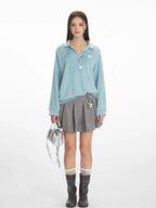 Model wearing a light blue fuzzy knit collared v-neck sweater with a grey pleated mini skirt, white and grey striped socks, and black boots.