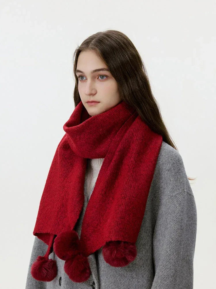 Close-up of a woman wearing a red knit scarf with pom-pom embellishments