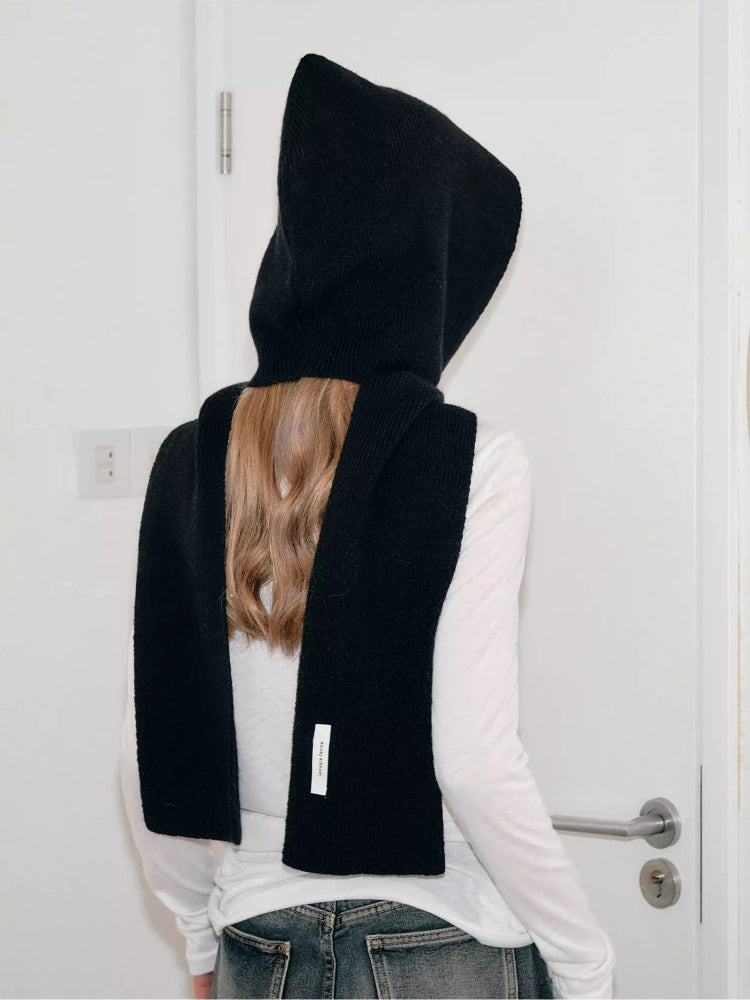 Back view of a woman wearing a black hooded scarf with a large bow detail.