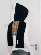 Back view of a woman wearing a black hooded scarf with a large bow detail.