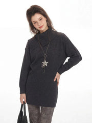Close-up of a woman wearing a charcoal grey oversized turtleneck knit tunic with a star pendant necklace.
