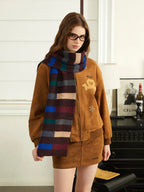 Woman wearing a brown bomber jacket, brown mini skirt, and a multi-colored striped scarf.