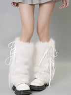 Front view of legs wearing white faux fur leg warmers with ribbon ties, complementing white shoes.