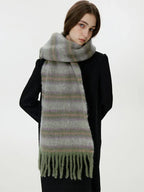 Side view of a woman wearing a black coat and a fuzzy, striped scarf with fringe detail.