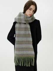 Side view of a woman wearing a black coat and a fuzzy, striped scarf with fringe detail.