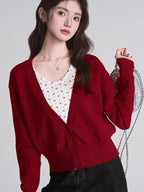 Close-up of a woman in a red V-neck cardigan and white floral tank top.