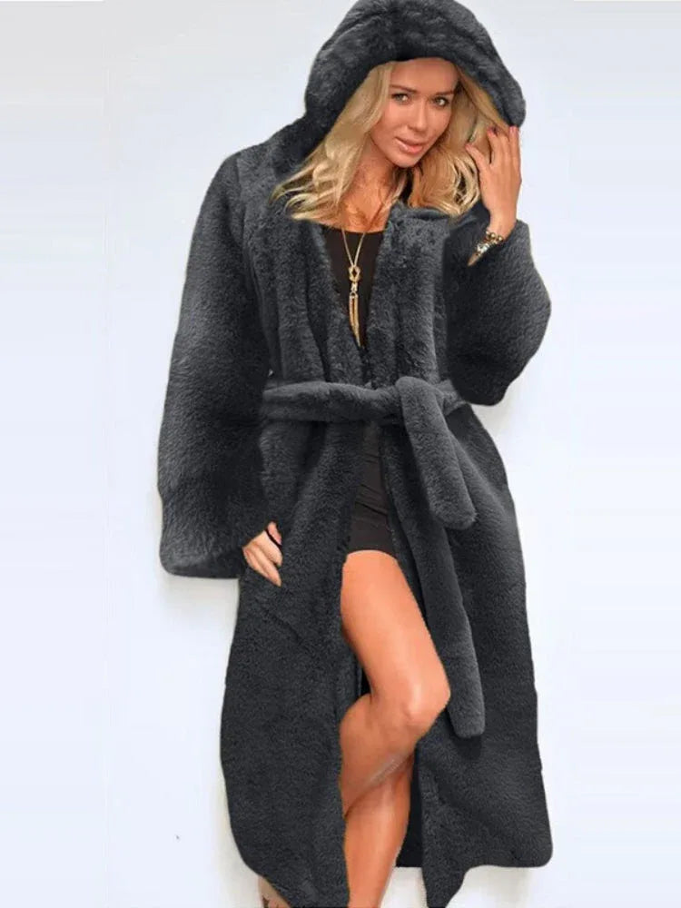 Woman wearing a long, dark grey faux fur coat with a hood and belt Main image