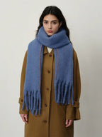Front view of a woman wearing a blue scarf and a brown coat