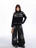 Woman holding a brown handbag and wearing a black zip-up knit sweater with a white fair isle dog pattern.
