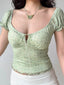 Close-up of a light green floral print top with puff sleeves and a sweetheart neckline.