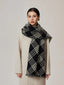 Woman in a cream coat and a black and white tartan scarf