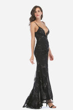 Woman wearing a black sequined formal gown with a high slit and deep V-neck, side view