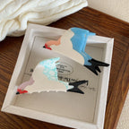 Two bird-shaped hair clips, one with blue wings and the other with blue-veined white wings, placed in a white box.