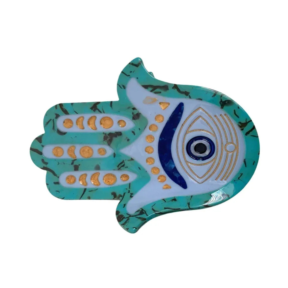 Close-up of a turquoise Hamsa hand accessory with an evil eye design. Main image