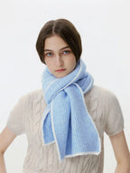 Woman wearing a light blue ribbed knit scarf with white trim