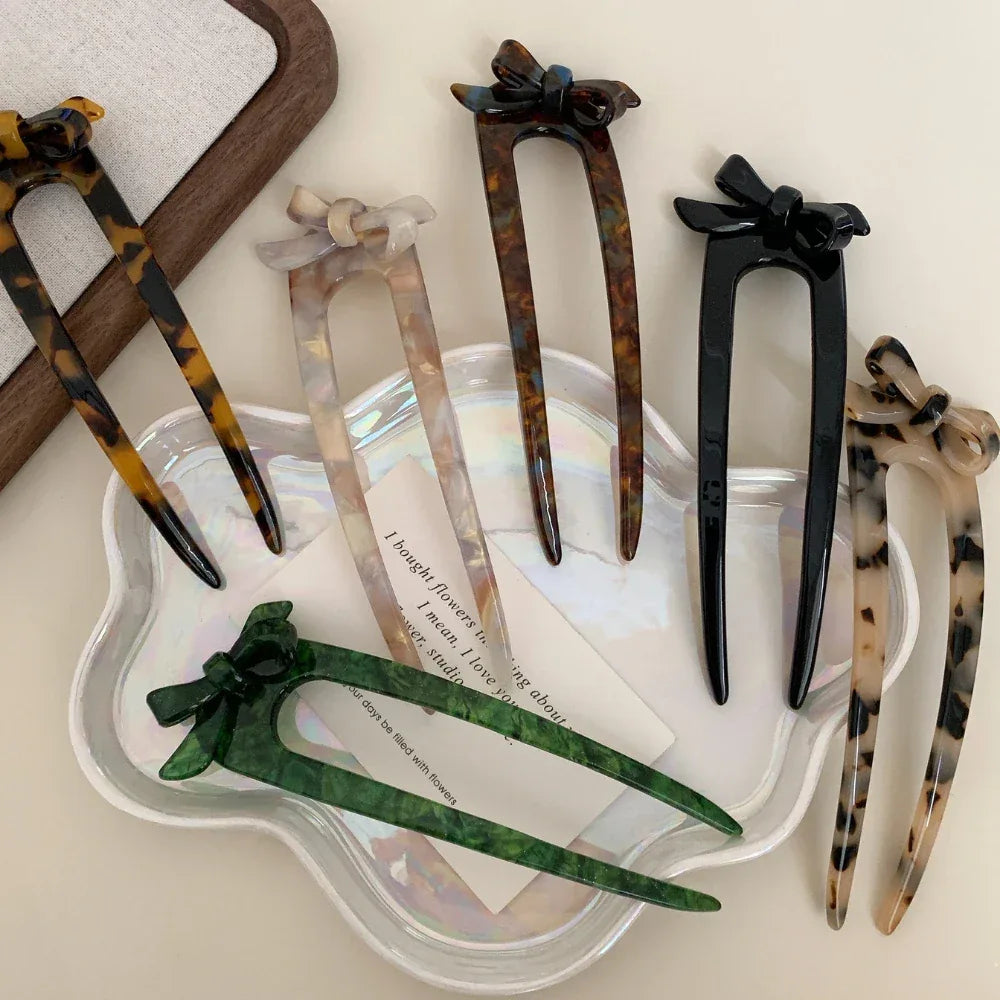 Various colorful hair accessories with bow details displayed on a white tray