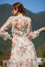 Back view of a woman wearing a floral print chiffon gown with tiered ruffles and bishop sleeves, showcasing the open back detail.