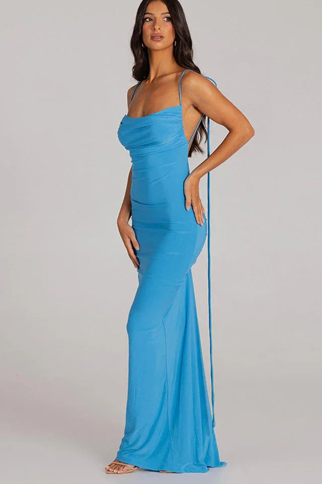 Side view of a woman in a long blue ruched dress with spaghetti straps and an open back
