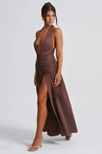 woman wearing a brown halter maxi dress with a deep v-neckline and high slit, showing the side profile and leg